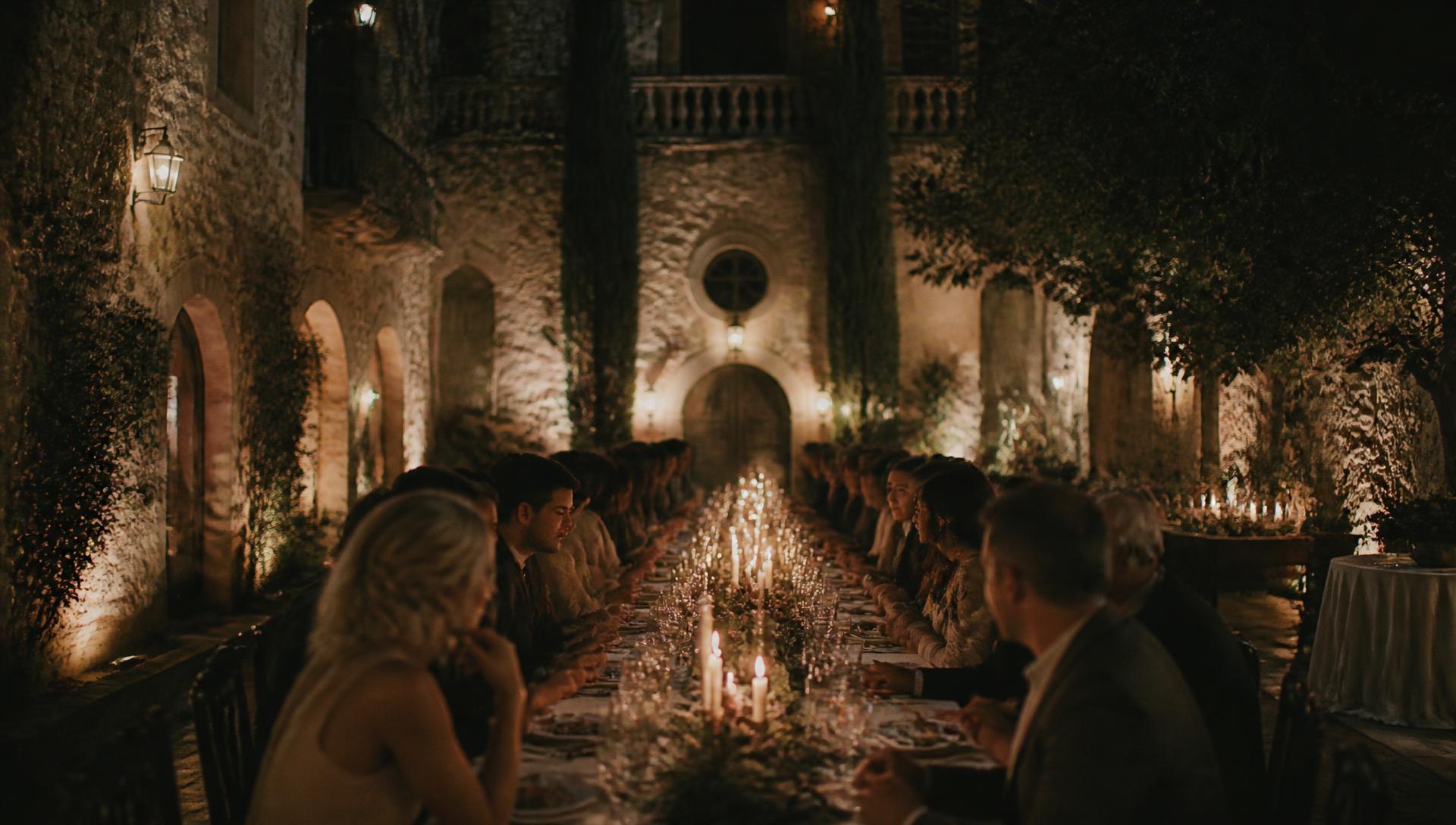 Candlelit long-table dinner in a historic stone courtyard