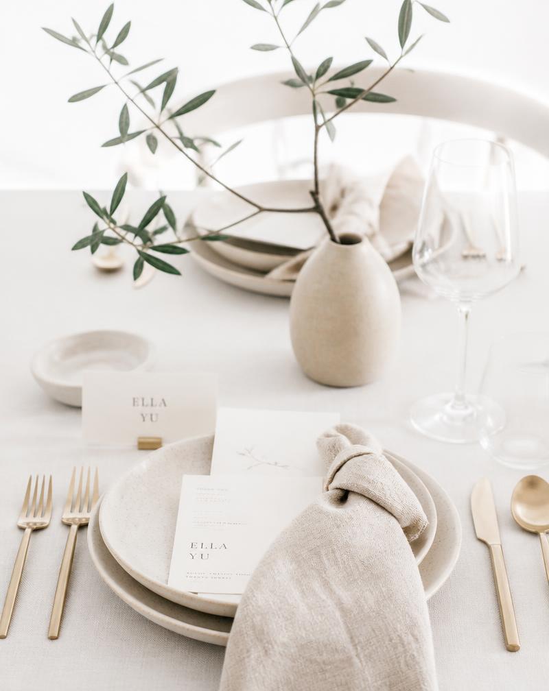 Minimalist linen table setting with stoneware and olive branch